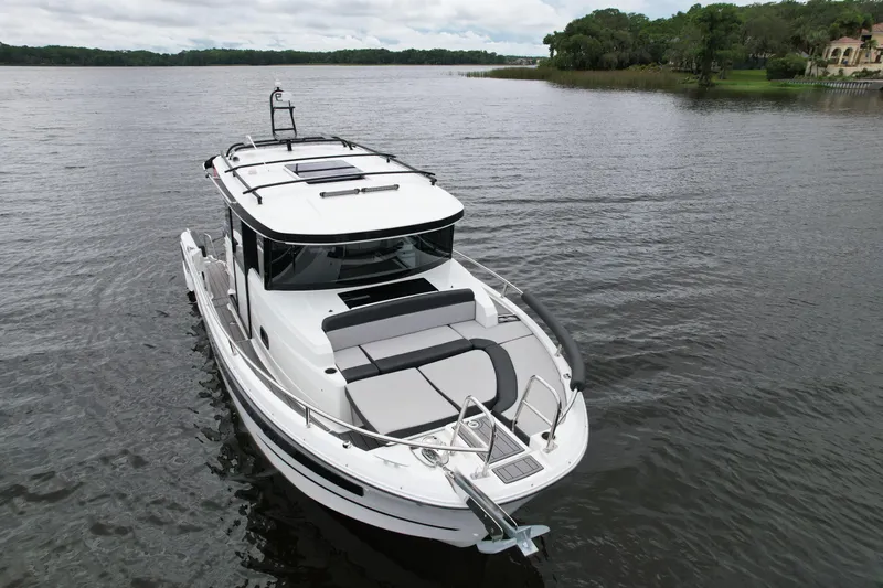  Yacht Photos Pics 2023 Jeanneau NC Sport 895 boat on a calm lake with lush shoreline.