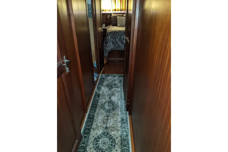 Sky To Sea Yacht Photos Pics Narrow hallway inside 1984 Hatteras 53 Extended Deckhouse Motor Yacht with wooden walls and patterned rug.