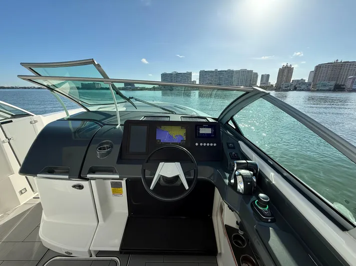 Yacht Photos Pics 2021 Aviara AV32 OB boat dashboard with navigation screens, steering wheel, and waterfront view.