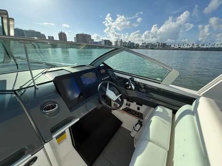  Yacht Photos Pics 2021 Aviara AV32 OB boat cockpit with modern controls, overlooking a scenic waterfront.