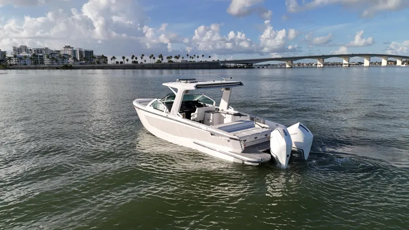  Yacht Photos Pics 2021 Aviara AV32 OB boat cruising near a bridge under a partly cloudy sky.