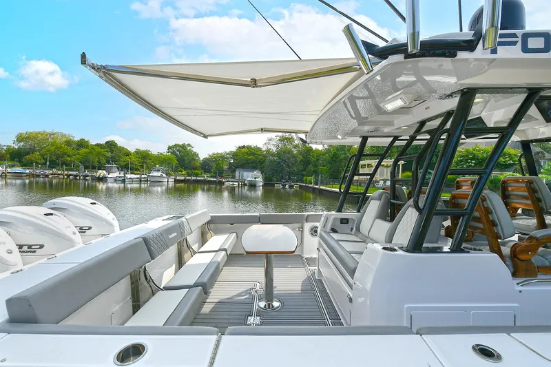 Fourtuna 2 Yacht Photos Pics 2023 Everglades 455 Center Console boat with spacious seating and canopy on a serene lake.