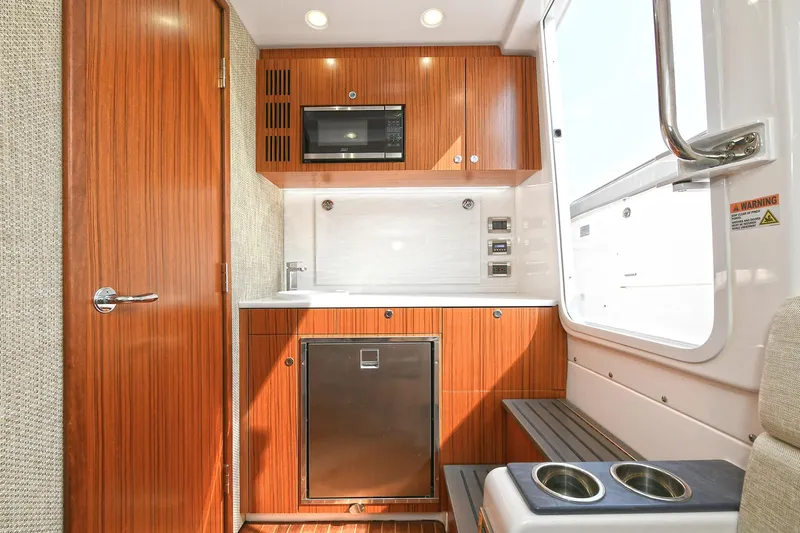 Fourtuna 2 Yacht Photos Pics Luxurious 2023 Everglades 455 Center Console boat interior with kitchenette and wood finish.