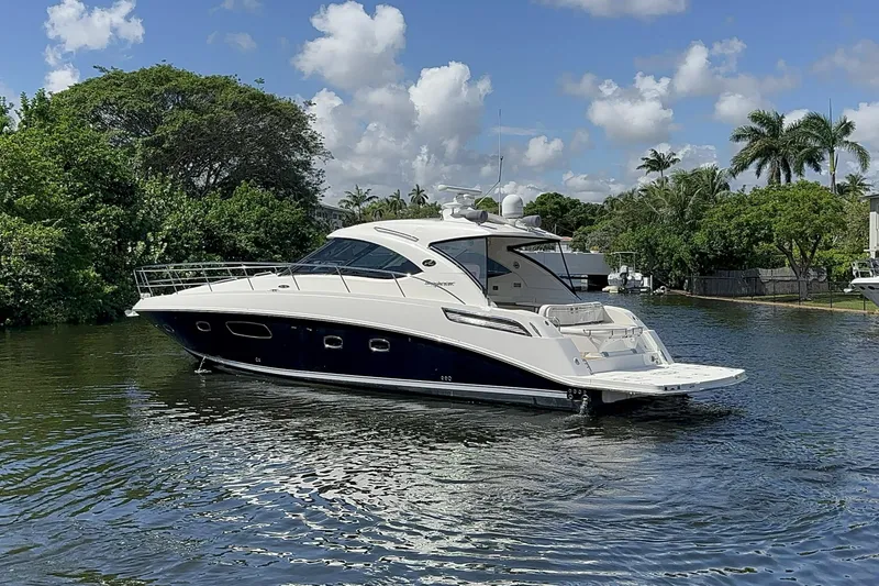  Yacht Photos Pics 2012 Sea Ray 470 Sundancer yacht on a serene waterway, surrounded by lush greenery.