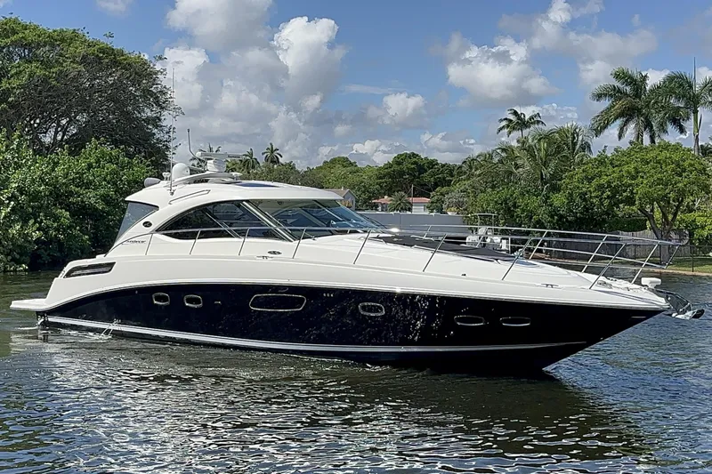  Yacht Photos Pics 2012 Sea Ray 470 Sundancer yacht on a sunny day, surrounded by lush greenery.