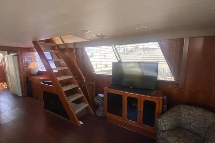 Sea Sharp Yacht Photos Pics 1990 Viking Motor Yacht interior with wooden stairs, TV, and cozy seating area.
