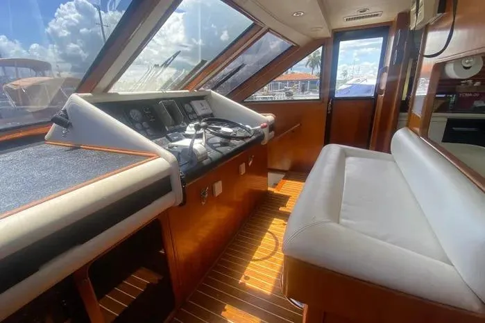 Sea Sharp Yacht Photos Pics 1990 Viking Motor Yacht interior with helm, wooden flooring, and cushioned seating.
