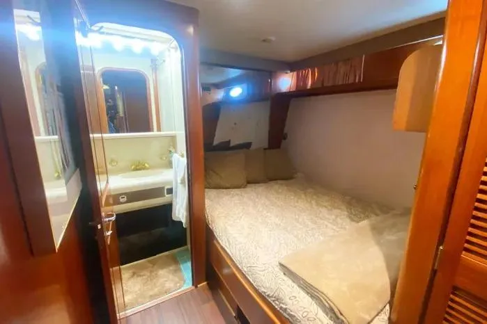 Sea Sharp Yacht Photos Pics Cozy bedroom and bathroom in a 1990 Viking Motor Yacht, featuring wood accents and soft lighting.
