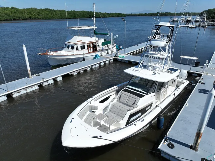 Happy Hour Yacht Photos Pics 2022 Pursuit s428 boat docked at marina, surrounded by calm waters and lush greenery.