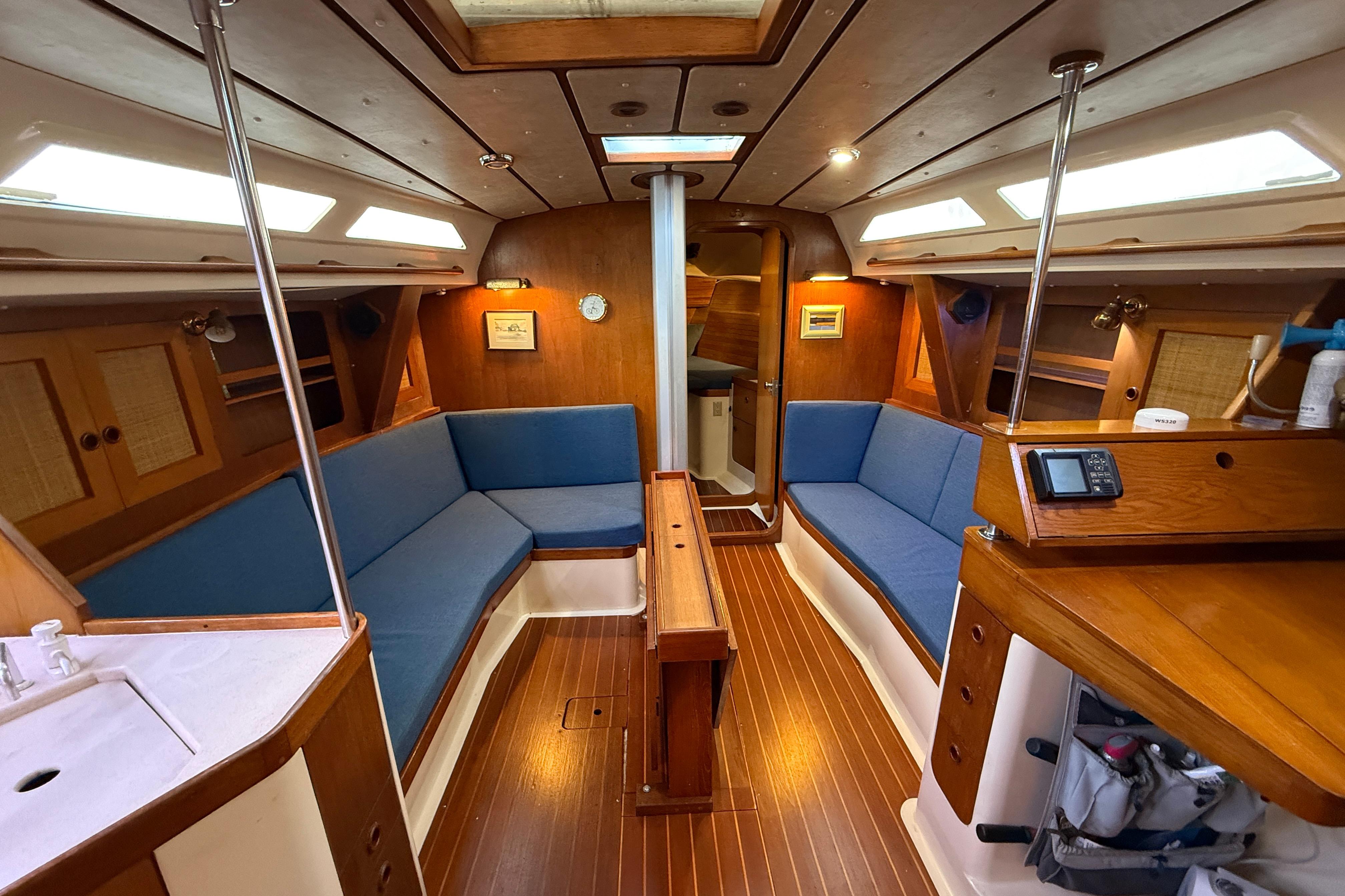 Interior of 1987 CS 40 sailboat with blue seating and wooden finishes.