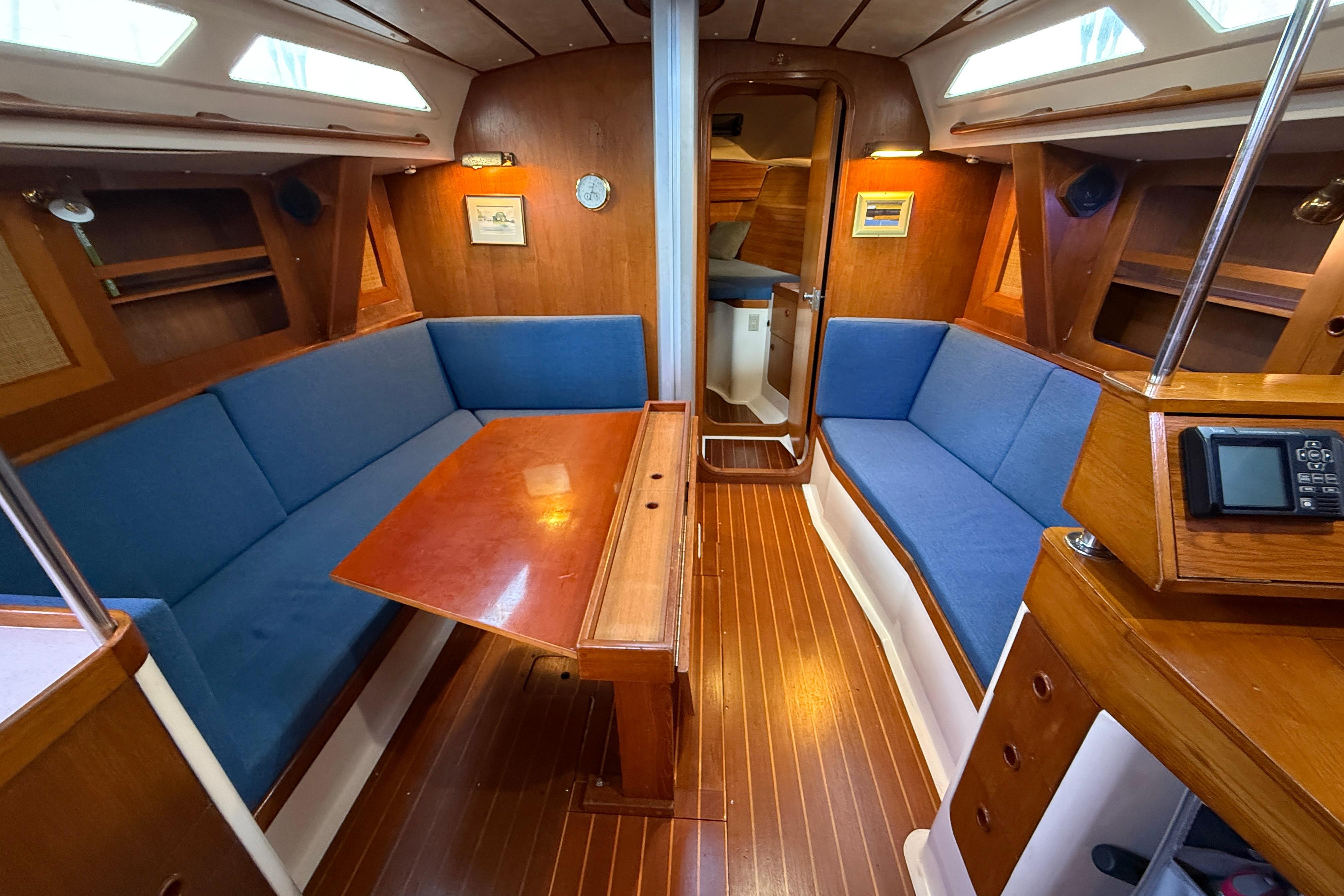Interior of a 1987 CS 40 sailboat with wooden finishes and blue seating.