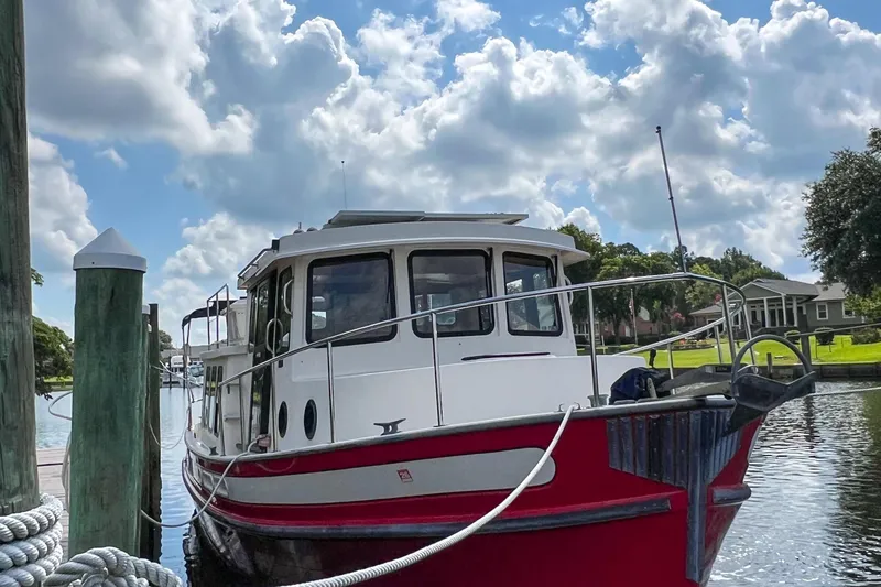 Mirage Yacht Photos Pics Red and white 1999 Nordic 32 boat docked under a cloudy sky.