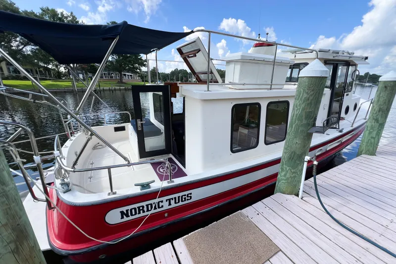Mirage Yacht Photos Pics 1999 Nordic Tugs 32 boat docked by a wooden pier on a sunny day.