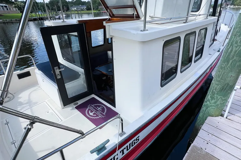 Mirage Yacht Photos Pics 1999 Nordic 32 boat docked, open cabin door, visible interior seating, and scenic waterfront.