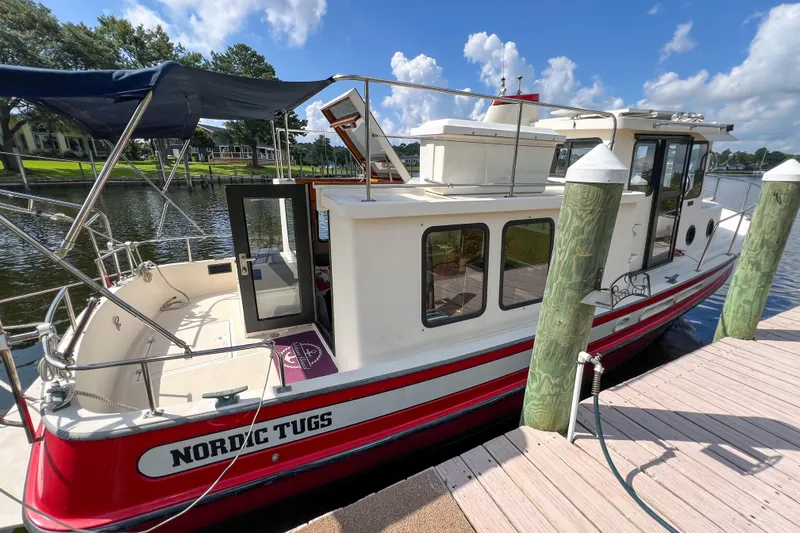 Mirage Yacht Photos Pics 1999 Nordic Tug 32 docked, featuring red and white design, under a clear blue sky.