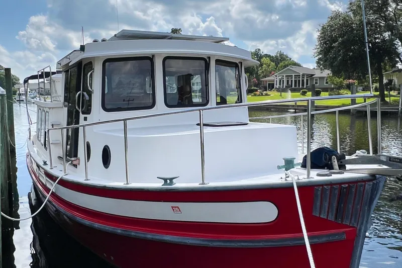 Mirage Yacht Photos Pics Red and white Nordic 32 boat from 1999 docked by a scenic waterfront.