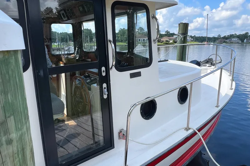 Mirage Yacht Photos Pics 1999 Nordic 32 boat docked by a serene waterfront, showcasing its cabin and railing.