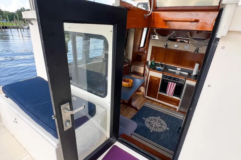 Mirage Yacht Photos Pics Interior view of a 1999 Nordic 32 boat, featuring a cozy kitchen and seating area.