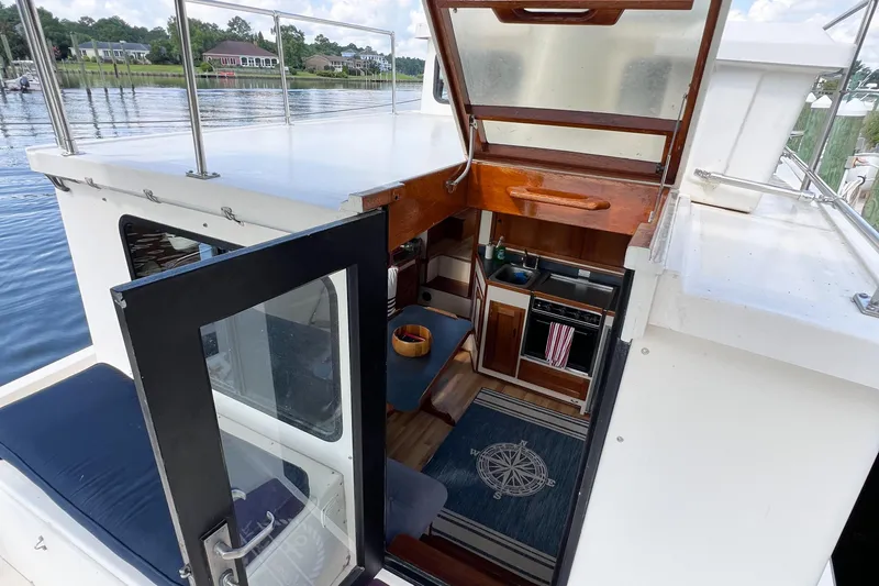 Mirage Yacht Photos Pics Interior view of a 1999 Nordic 32 boat, featuring a compact kitchen and seating area.