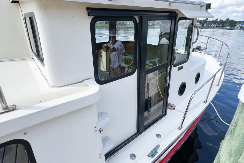 Mirage Yacht Photos Pics 1999 Nordic 32 boat docked, featuring white exterior and glass door, reflecting waterfront scenery.