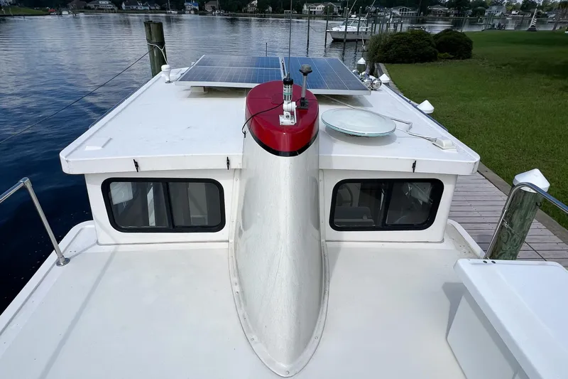 Mirage Yacht Photos Pics Nordic 32 boat (1999) with solar panels, docked by a serene waterfront.