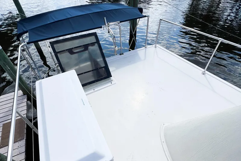 Mirage Yacht Photos Pics Nordic 32 boat deck, 1999 model, with blue canopy and railing by the water.