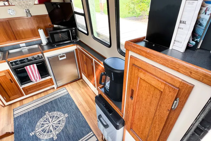 Mirage Yacht Photos Pics Cozy Nordic 32 boat kitchen with wood cabinets, appliances, and nautical-themed rug, 1999 model.