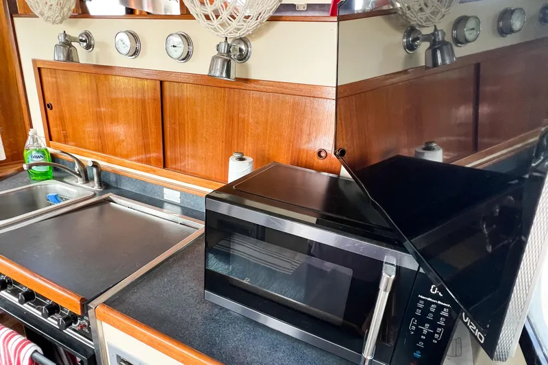 Mirage Yacht Photos Pics Kitchen area in a 1999 Nordic 32 boat with microwave, stove, and sink.