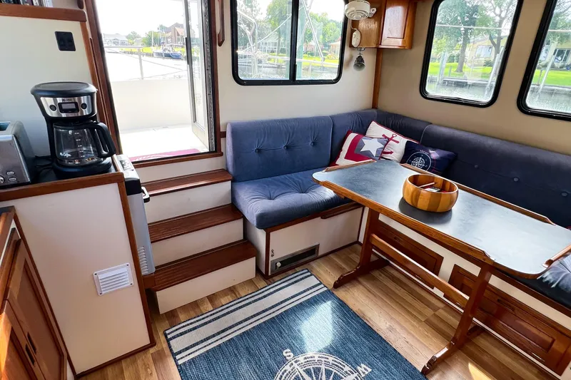 Mirage Yacht Photos Pics Cozy Nordic 32 boat interior, featuring a dining area with blue seating and nautical decor.