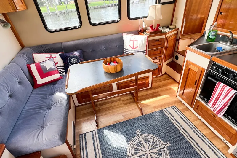 Mirage Yacht Photos Pics Cozy interior of a 1999 Nordic 32 boat with nautical-themed decor and compact kitchen.