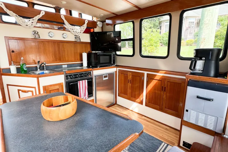 Mirage Yacht Photos Pics Cozy Nordic 32 boat kitchen interior with wood cabinets, appliances, and large windows, 1999 model.