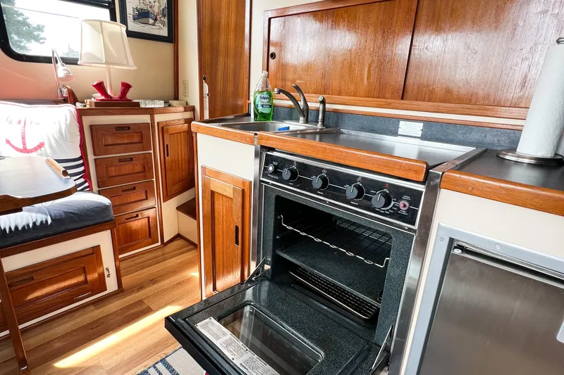 Mirage Yacht Photos Pics Cozy Nordic 32 boat kitchen with wood cabinetry, open oven, and sink, built in 1999.