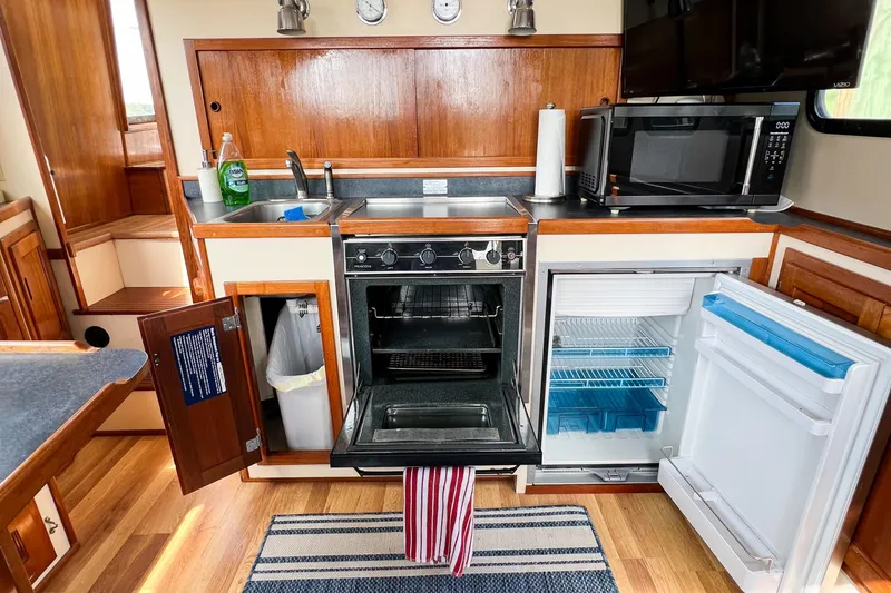 Mirage Yacht Photos Pics Kitchen area in a 1999 Nordic 32 boat with stove, sink, and open fridge.