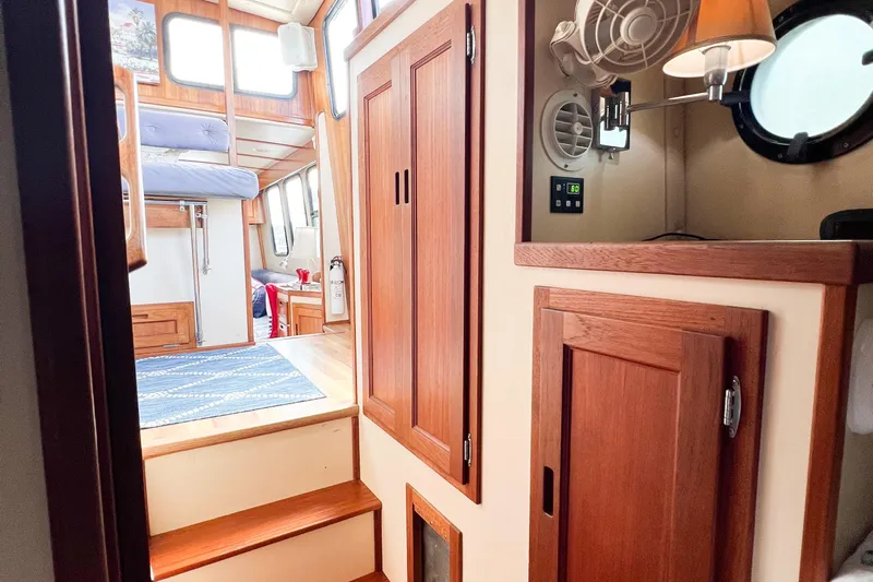 Mirage Yacht Photos Pics Interior of a 1999 Nordic 32 boat with wooden cabinetry and cozy seating area.