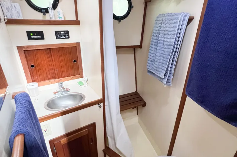 Mirage Yacht Photos Pics Compact bathroom in a 1999 Nordic 32 boat, featuring sink, towels, and wooden accents.