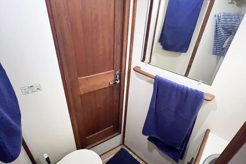 Mirage Yacht Photos Pics Compact bathroom in a 1999 Nordic 32 boat, featuring wooden door and blue towels.