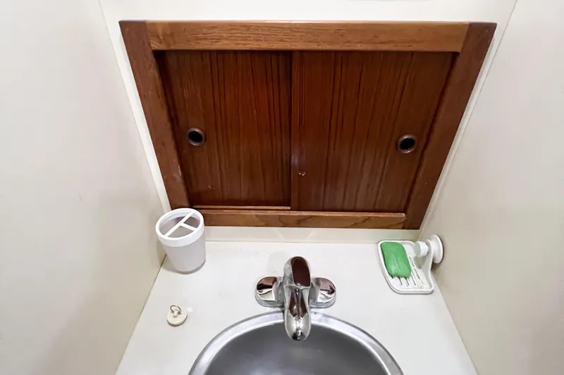 Mirage Yacht Photos Pics Small bathroom sink with wooden cabinet, soap dish, and cup holder in Nordic 32, 1999 model.
