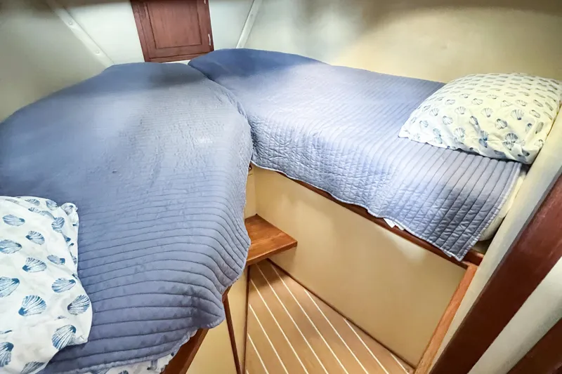 Mirage Yacht Photos Pics Cozy cabin interior of 1999 Nordic 32 boat with blue bedding and wooden accents.