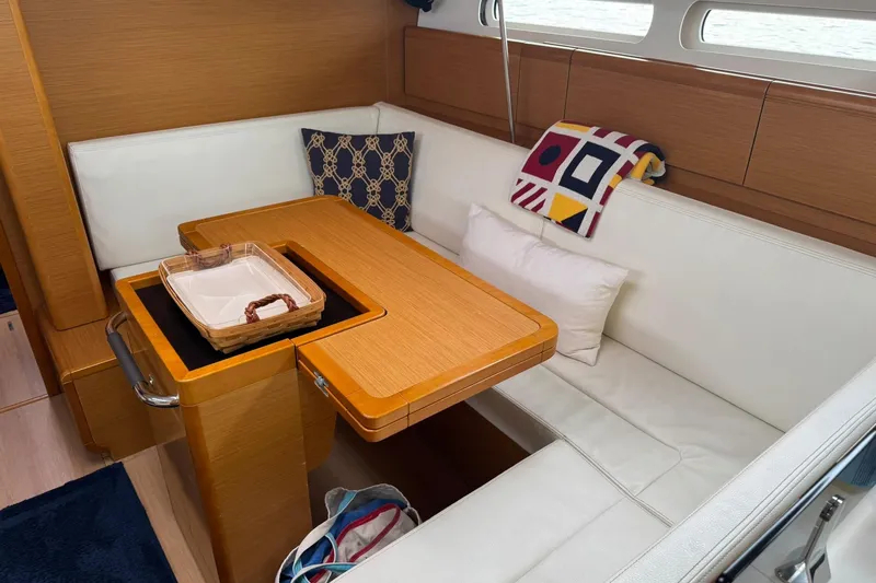 Kairos Yacht Photos Pics Cozy interior of 2013 Jeanneau 409 sailboat with wooden table and white seating.