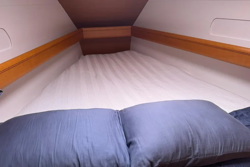 Kairos Yacht Photos Pics Cozy cabin bed in 2013 Jeanneau 409 sailboat with wooden accents and blue bedding.