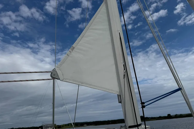 Kairos Yacht Photos Pics Sail of Jeanneau 409 yacht against a partly cloudy sky.