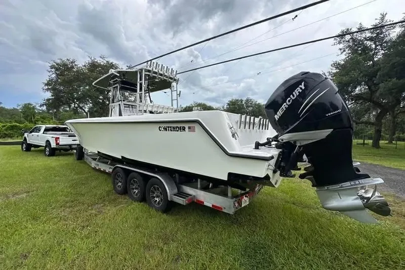  Yacht Photos Pics 2019 Contender 39 ST boat on trailer, with Mercury outboard engine, parked on grass.