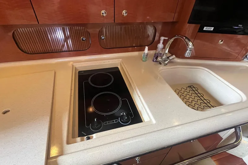 Chance Encounter Yacht Photos Pics 2004 Sea Ray 340 Sundancer kitchen with stove, sink, and wooden cabinetry.