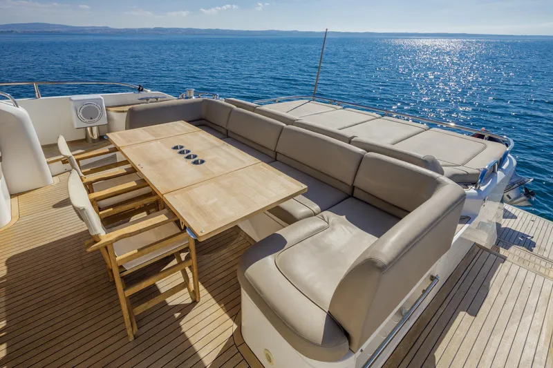 Black Sugar Yacht Photos Pics Luxurious 2010 Princess V78 yacht deck with seating and dining area, overlooking serene ocean waters.