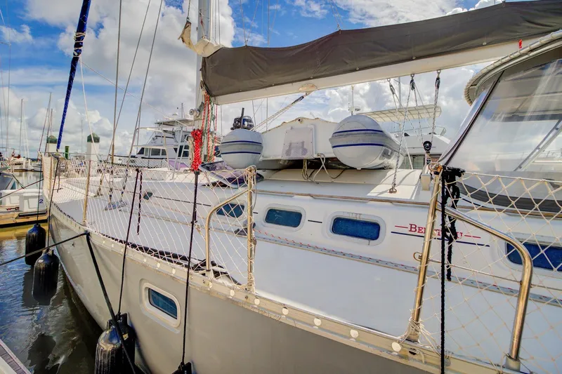 Grace Yacht Photos Pics 1994 Beneteau 510 sailboat docked, featuring netted railings and lifebuoys under a cloudy sky.