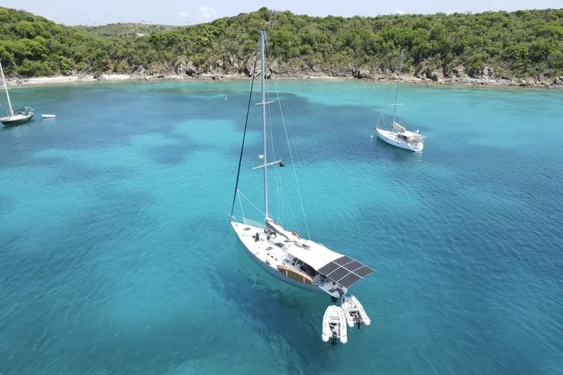Grace Yacht Photos Pics Sailboats anchored in clear turquoise water near a lush, green coastline.