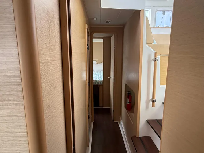 Feel The Moon Yacht Photos Pics Narrow hallway inside 2010 Lagoon 400 Owner's Version yacht, featuring wooden paneling and stairs.