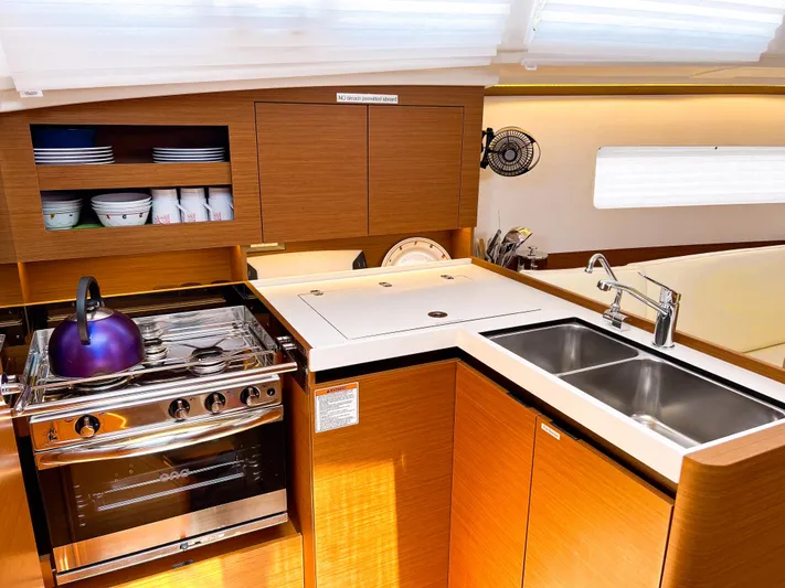 Soca Sleigh Yacht Photos Pics 2024 Jeanneau Sun Odyssey 380 yacht kitchen with stove, sink, and wooden cabinetry.