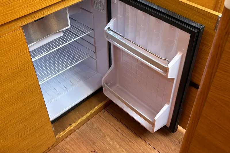 Abide Yacht Photos Pics Open refrigerator inside 2018 X-Yachts X4.9, showcasing wooden interior design.
