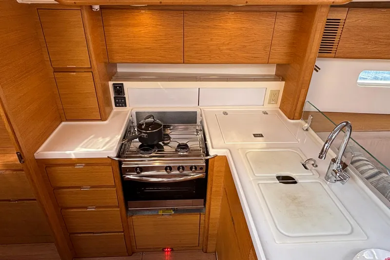Abide Yacht Photos Pics 2018 X-Yachts X4.9 yacht kitchen with stove, sink, and wooden cabinetry.